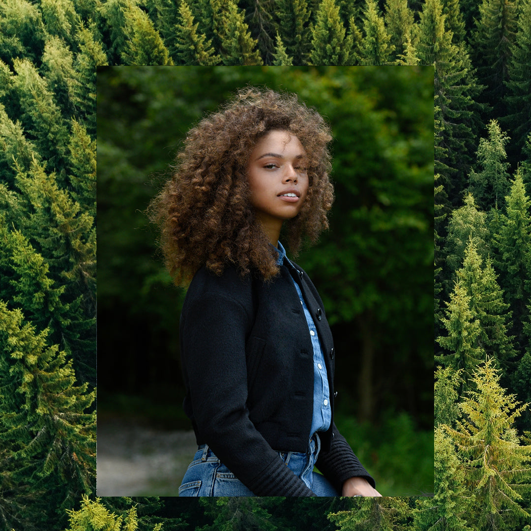 Sentaler Collarless Bomber Jacket with Knit Waistband featured in Baby Alpaca and available in Black. Seen from side on female model who is wearing the coat open.