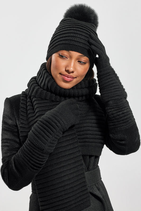 Sentaler Adult Ribbed Gloves, Adult Ribbed Hat with Oversized Fur Pompon, Adult Ribbed Scarf featured in Baby Alpaca and available in Black. Seen from front on model.