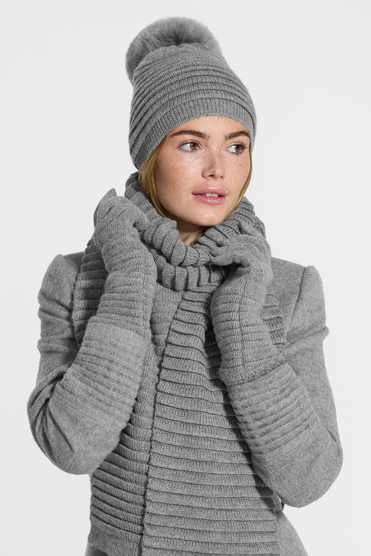Sentaler Adult Ribbed Scarf, Ribbed Hat with Oversized Fur Pompon, Ribbed Gloves featured in Baby Alpaca and available in Grey. Seen from side above the waist on model.