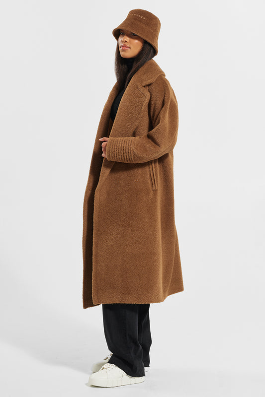 Sentaler Bouclé Alpaca Long Oversized Notched Collar Coat featured in Bouclé Alpaca and available in Caramel Café. Seen from side wearing the Bouclé Alpaca Bucket Hat in Caramel Café.Sentaler Bouclé Alpaca Long Oversized Notched Collar Coat featured in Bouclé Alpaca and available in Caramel Café. Seen from side wearing Bouclé Alpaca Bucket hat.